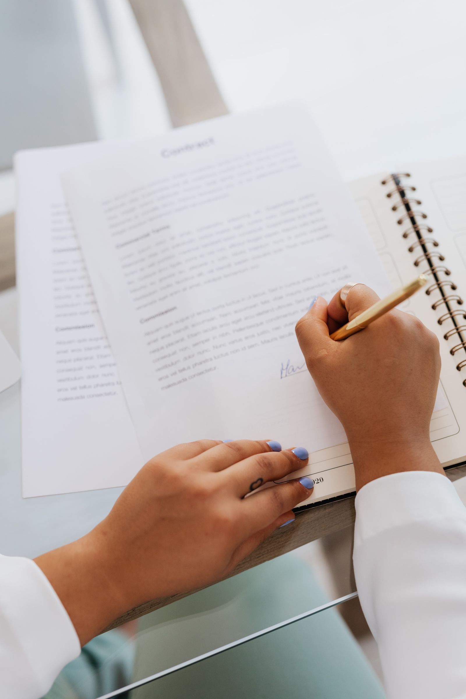 Person unterschreibt mit einem Stift ein Vertragsdokument auf einem Schreibtisch