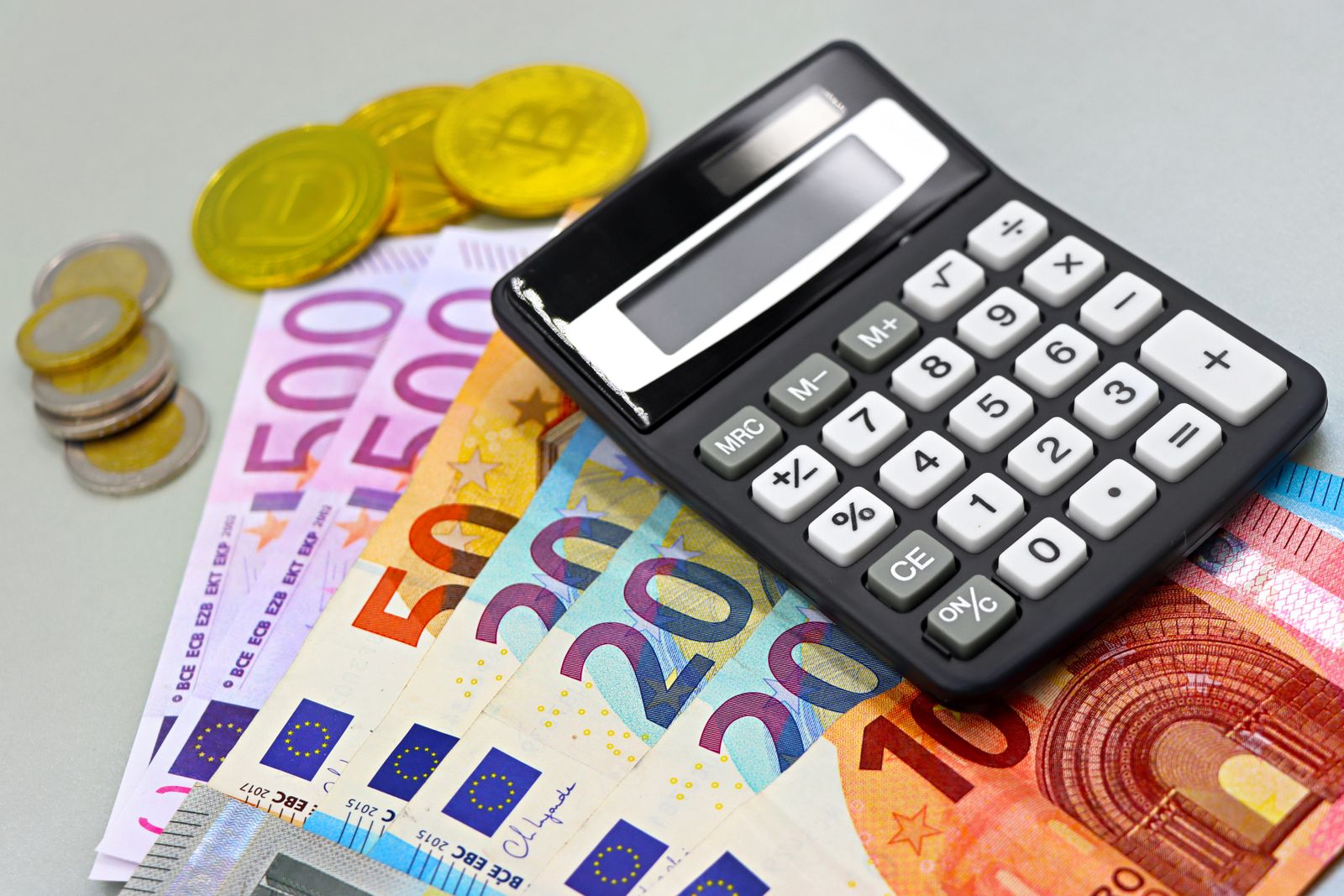 Euro-Geldscheine, Münzen und ein Taschenrechner auf einem Tisch