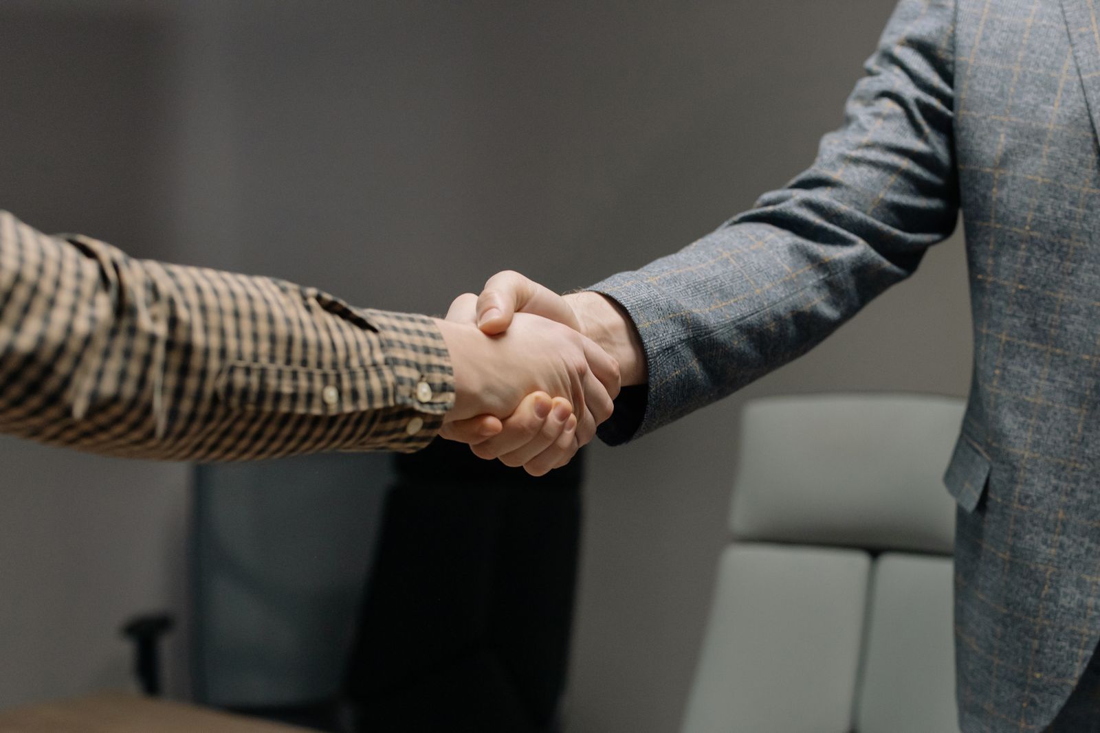 Zwei Personen geben sich in einem Büro die Hand zur Begrüßung